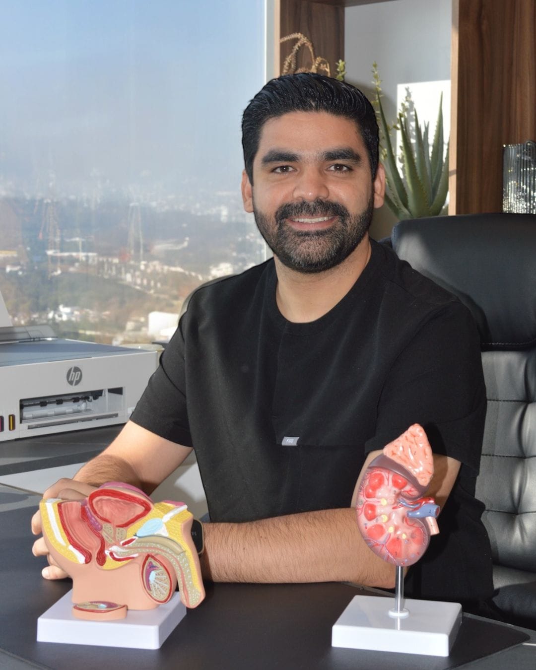 Urólogo oncólogo en consultorio médico con modelos anatómicos de riñón y próstata.